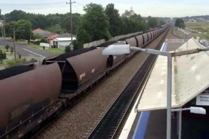 Loaded coal train passes suburban station