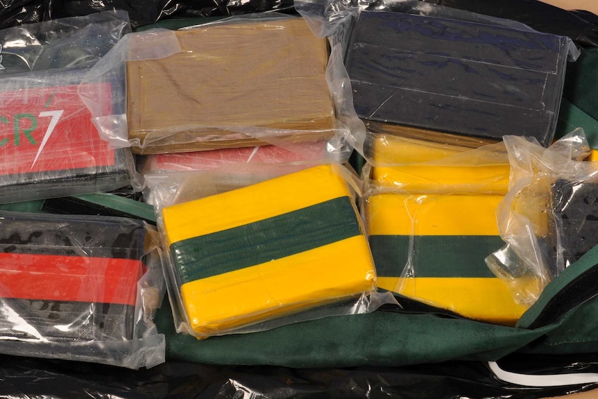 A close-up shot of rectangle blocks wrapped in tape and plastic, allegedly containing drugs.