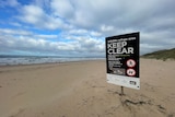 A beach with a keep clear sign