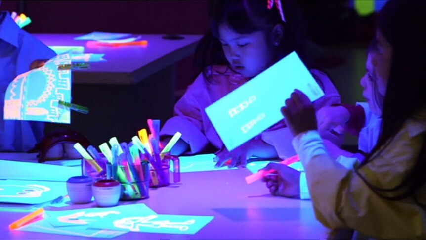 Children drawing in a room with ultraviolet light