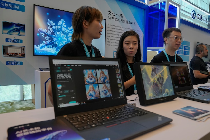 Sales people stand in front of laptops in China.