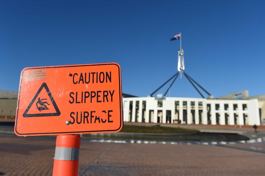 A "caution slippery surface" warning sign is seen outside Parliament House,