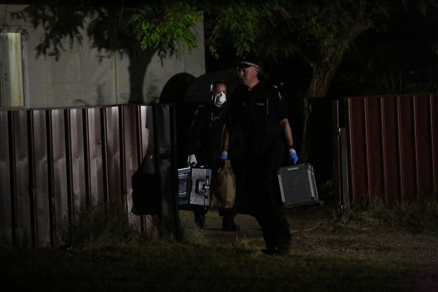 Police in dark blue uniforms leave a house carrying cases.
