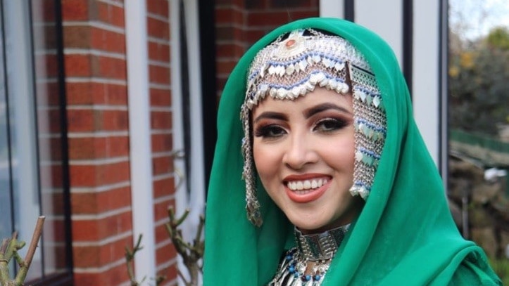 Shamsiya wearing green traditional clothing with silver accents and jewelry. 