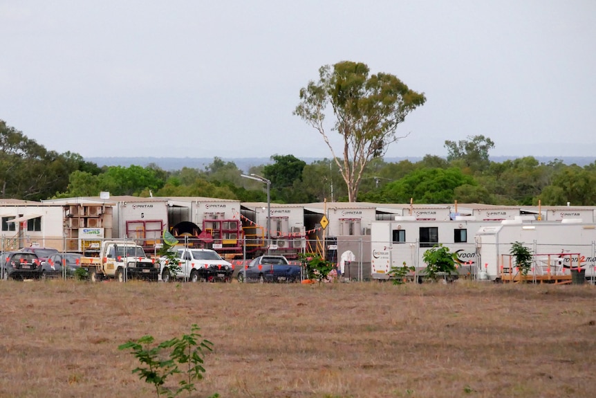 Demountable buildings, vans and vehicles set up in a camp in a grassy field