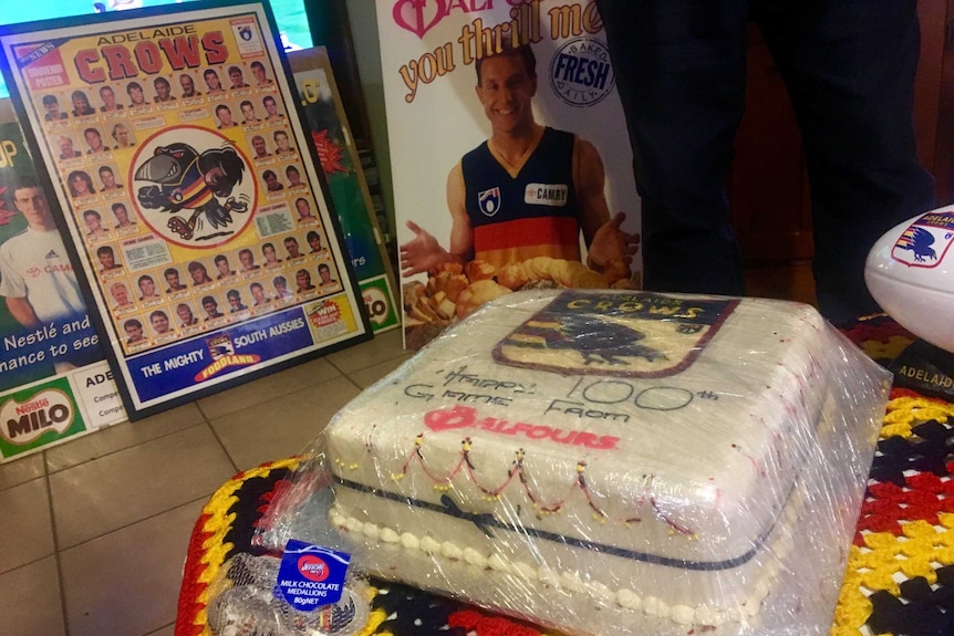 A cake with the Adelaide Crows' logo that says Happy 100th Game from Balfours