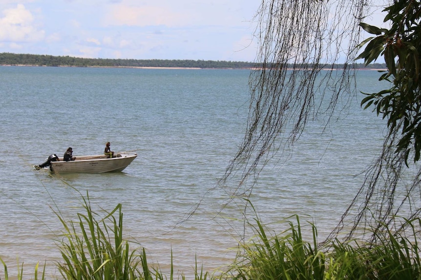 Teenage boys wait for a line while they fish from a tiny off the beach at Maningrida.