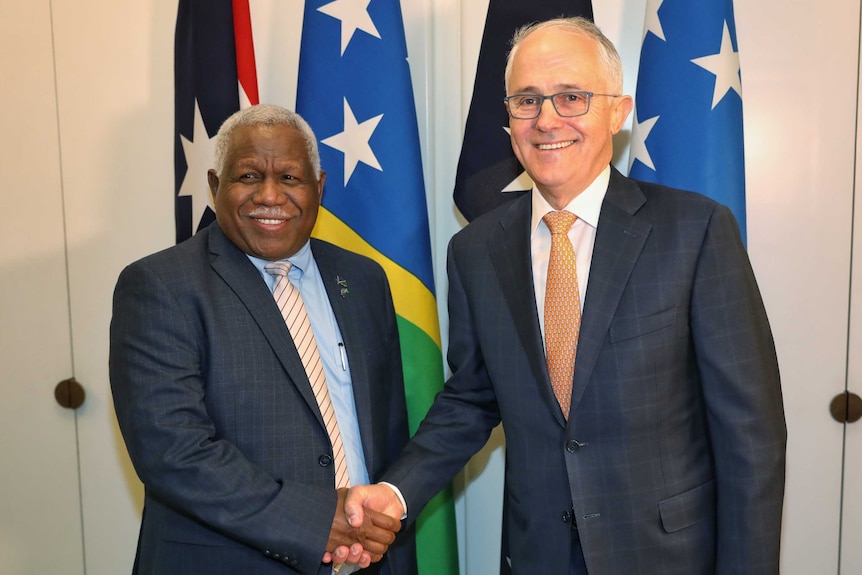 Malcolm Turnbull and Rick Houenipwela stand side by side, smiling while shaking hands.