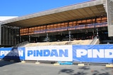 A wide show of a construction project showing a building part-completed behind blue and white Pindan fence banners.