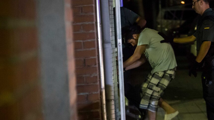 Police lead a man through a doorway.