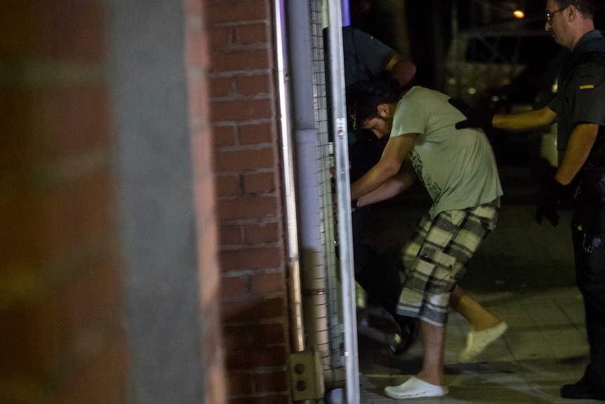 Police lead a man through a doorway.