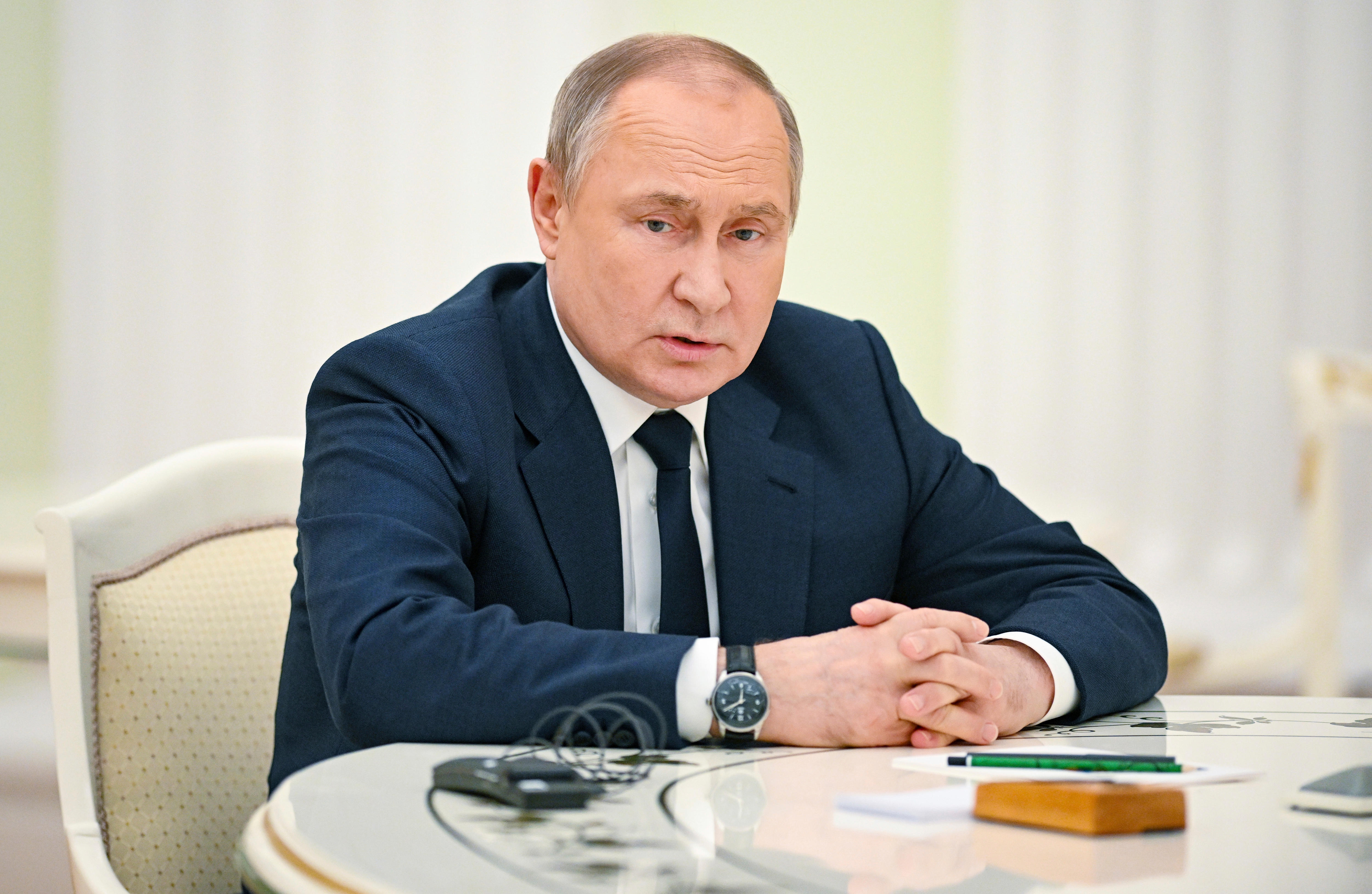 Middle aged man in navy suit seated at white table.