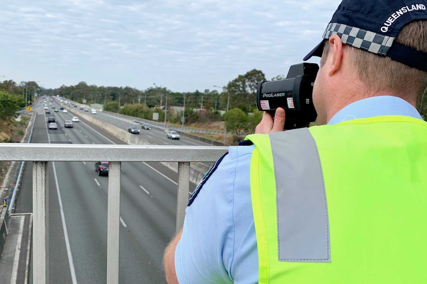 A Gold Coast road policing officer uses speed gun to monitor motorists on the M1.