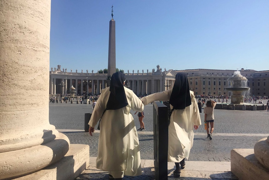 Two nuns walk hand in hand as they enter St. Peter's Square at the Vatican.
