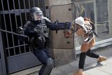 Riot police officers clash with a protester during a French demonstration