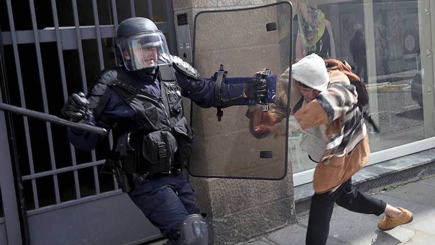 Riot police officers clash with a protester during a French demonstration