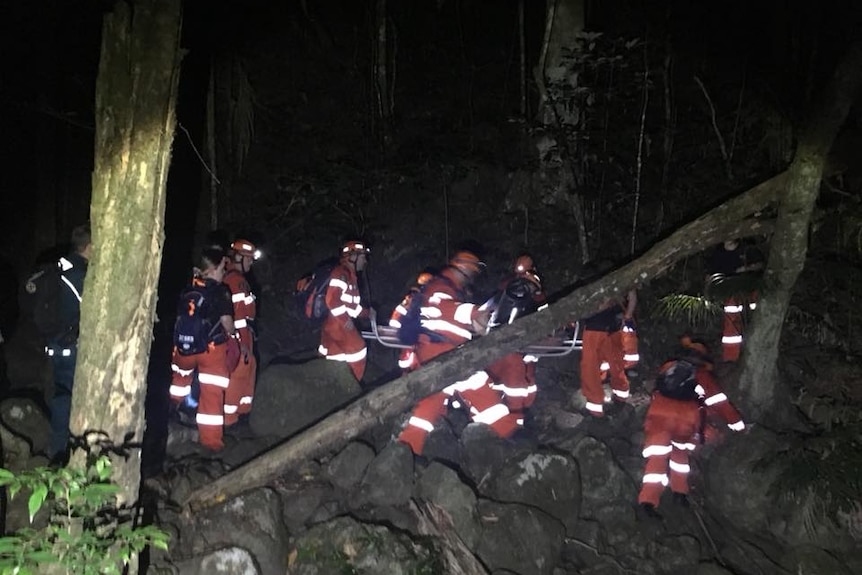 A group of SES rescuers dressed in orange carry out a rescue in the dark