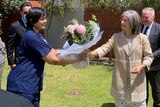 A woman in navy scrubs received a bouquet of flowers from another woman