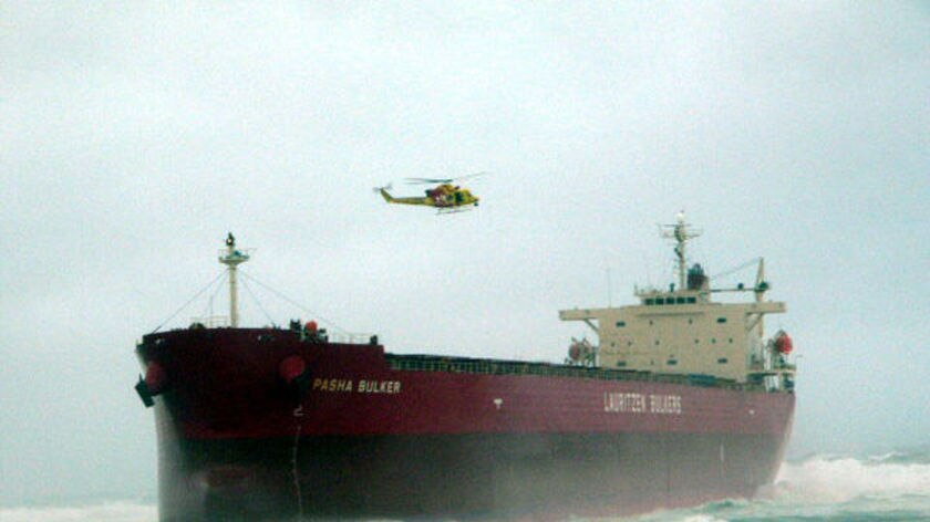 Rescue helicopter hovers over the grounded ship.