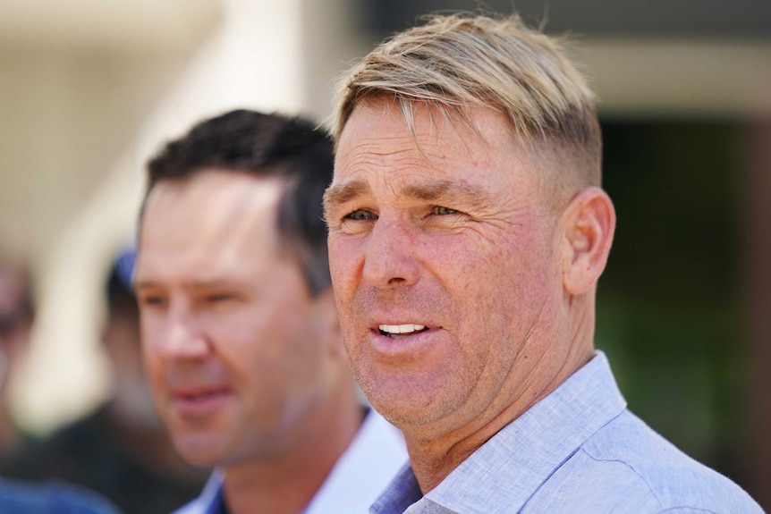 Shane Warne speaks at a press conference. Ricky Ponting is in the background.