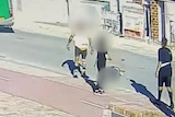 A still image taken from CCTV showing three teenagers standing on a street near a man on the ground, with identities blurred.