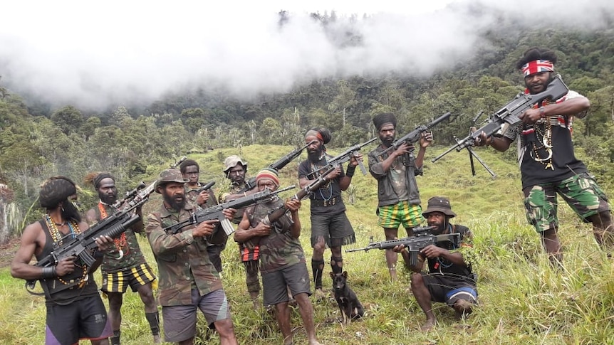 Egianus and his rebel army stand together holding guns.