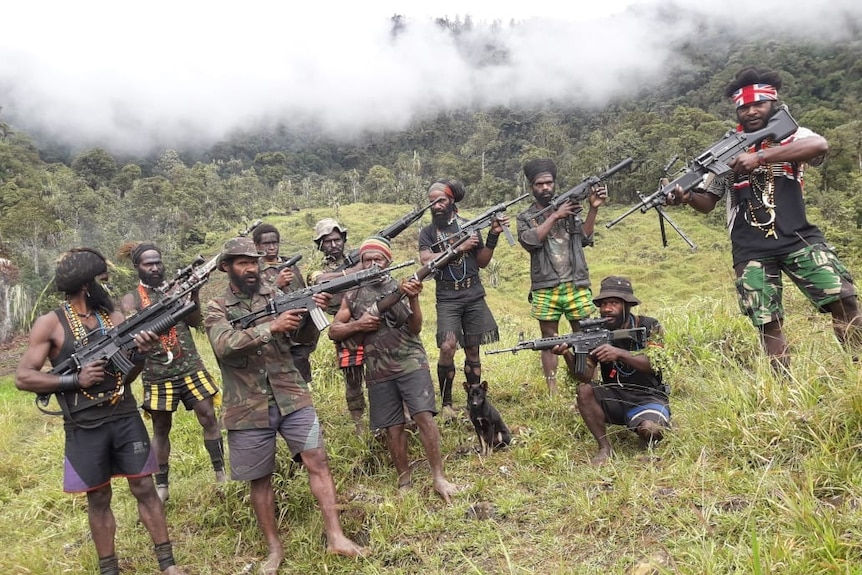 Egianus and his rebel army stand together holding guns.