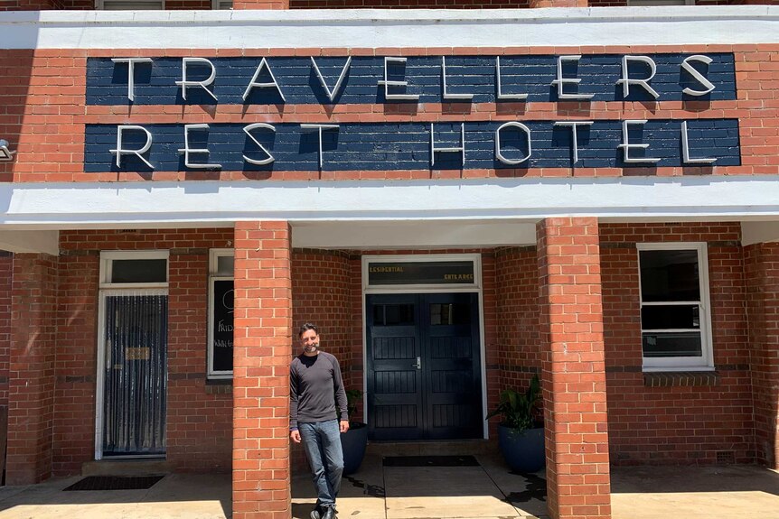 Adrian Thompson standing under 'Travellers Rest Hotel' sign, a brick country pub.