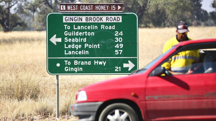 A directional sign on a country road with a car blocking traffic