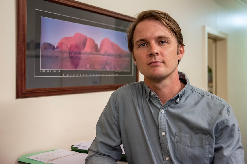 A man stands in his office looking at the camera