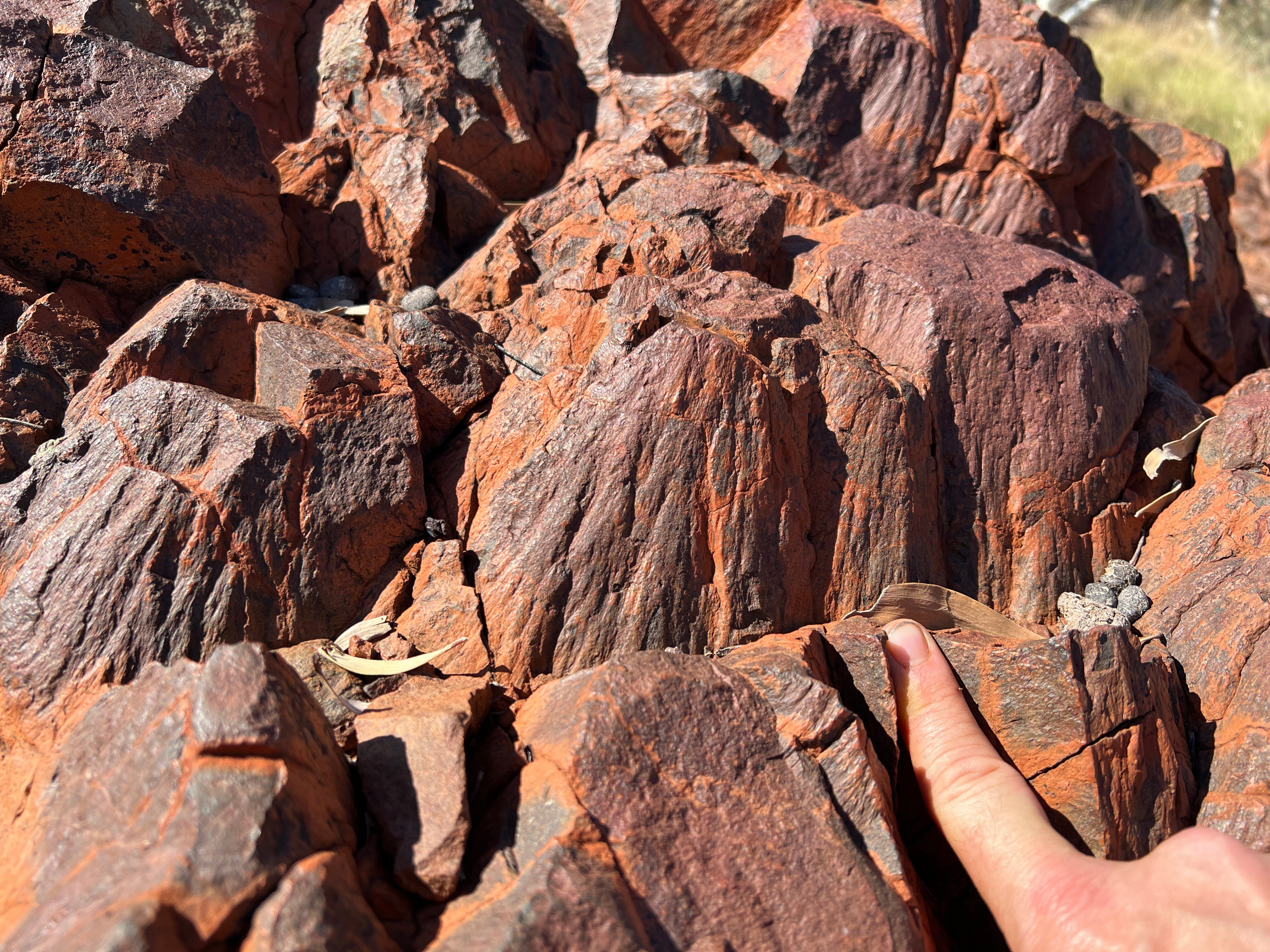 Red and grayish rocks pointing upwards, a finger points at them.