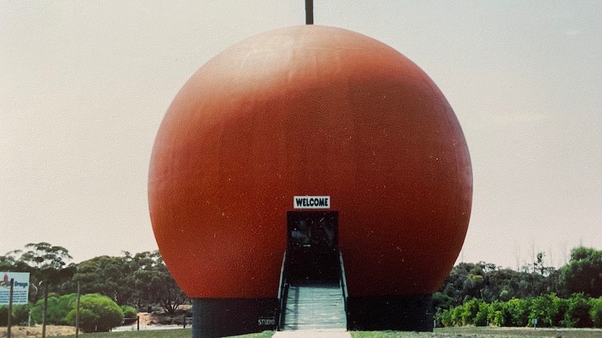 A giant orange sphere with stairs leading into it.