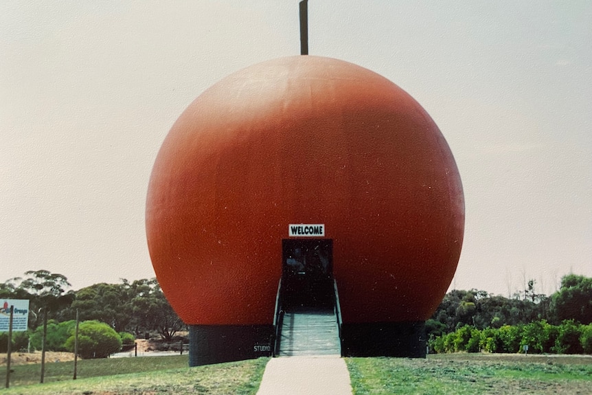 A giant orange sphere with stairs leading into it.