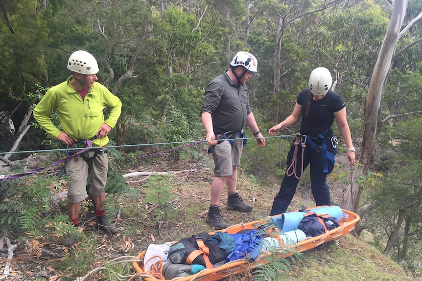 A team prepares to lower a rescuer down a cliff.