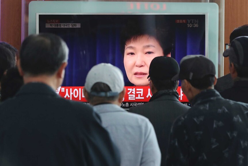 People watch a TV screen showing the live broadcast of South Korean President Park Geun-hye's address at Seoul Railway Station