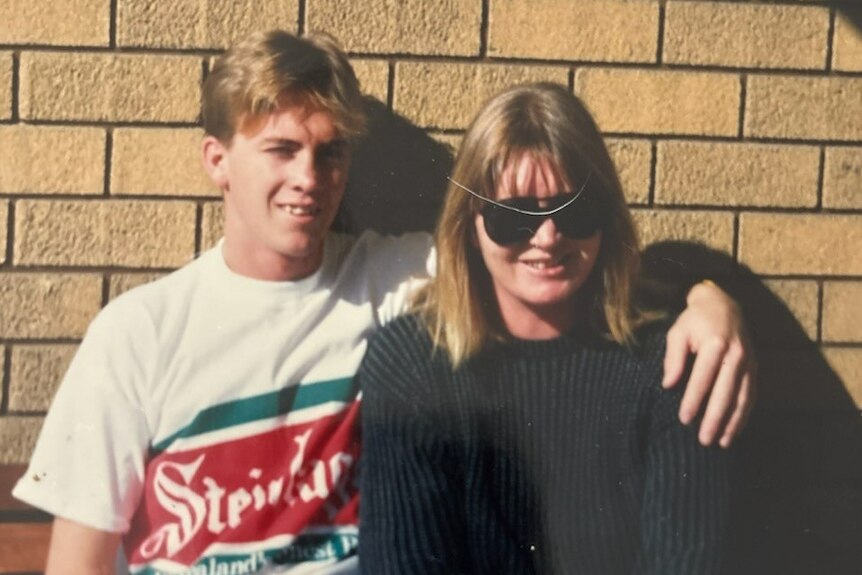 A teenage boy and his smiling mother.