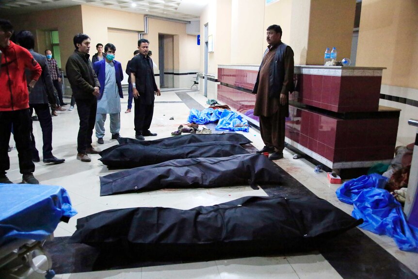 Afghan men look for their relatives among body bags lined up on a hospital floor.