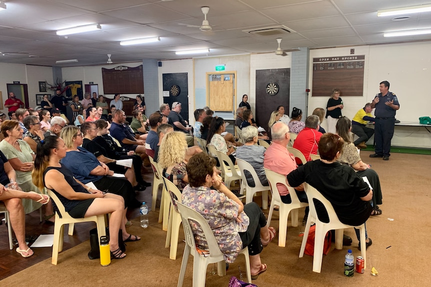 A group of people in a room listening to authorities speak