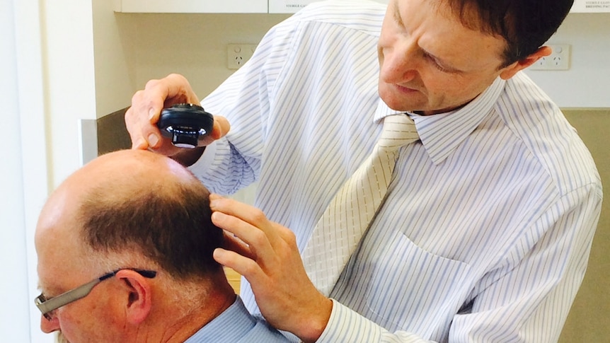 Doctor checking a man's head for skin cancer.