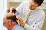 Doctor checking a man's head for skin cancer.