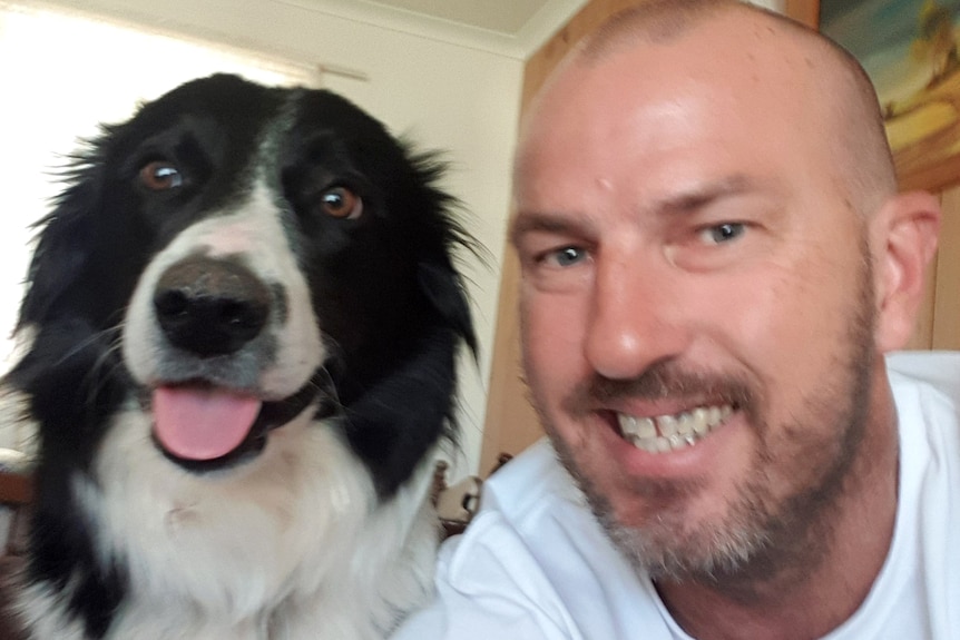 A man and a border collie both appear to smile in a selfie