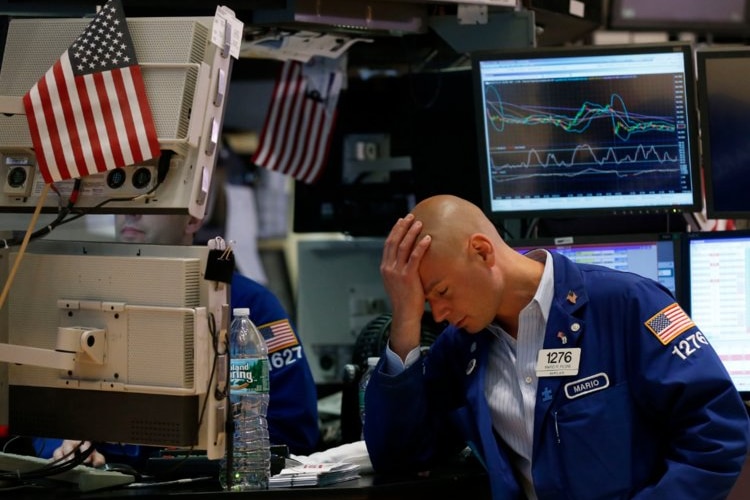 A Wall Street trader rests his head in his hand after a tough day