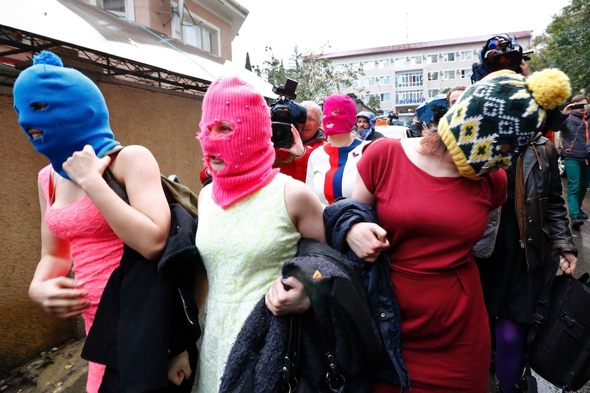Masked members of the Russian band Pussy Riot leave police station
