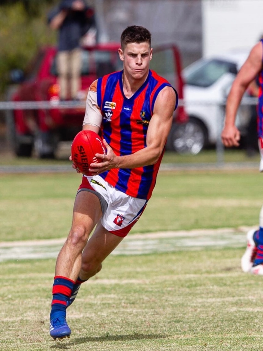 A man in a blue and red football jumper with a ball.