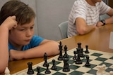 Nine-year-old Brock Anderson stares at a chess board, mid-game.