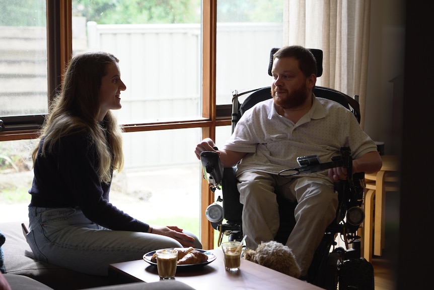 Man in a wheelchair with a woman sitting next to him.