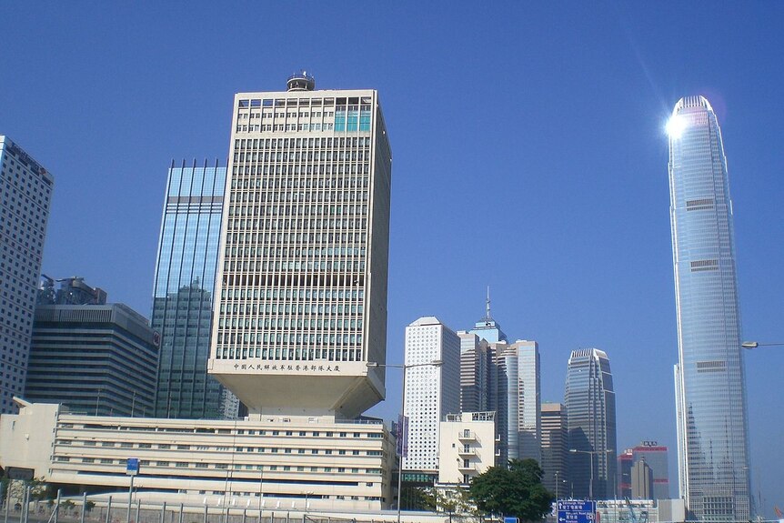 Hong Kong skyline with the boxy PLA garrison building in the foreground in front of blue skies.