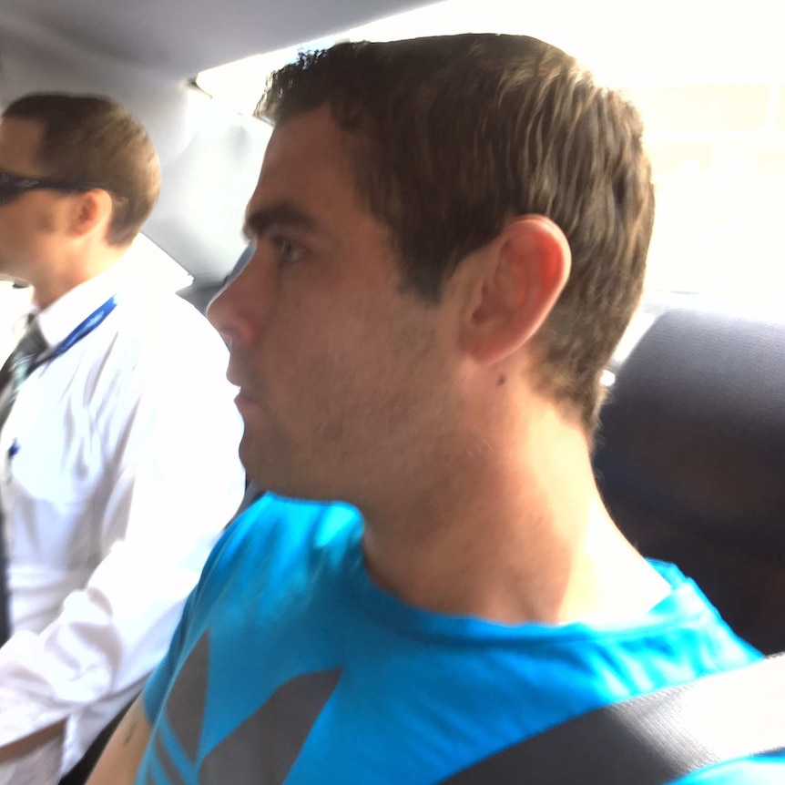 Judd Lees with plain clothes policeman in the back seat of a car
