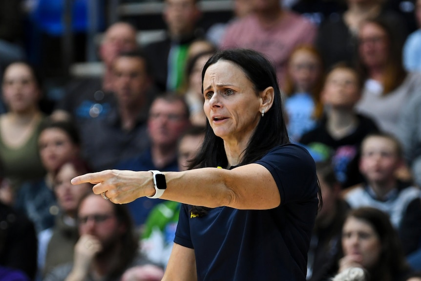 Sandy Brondello points as she stands on the basketball court sideline.