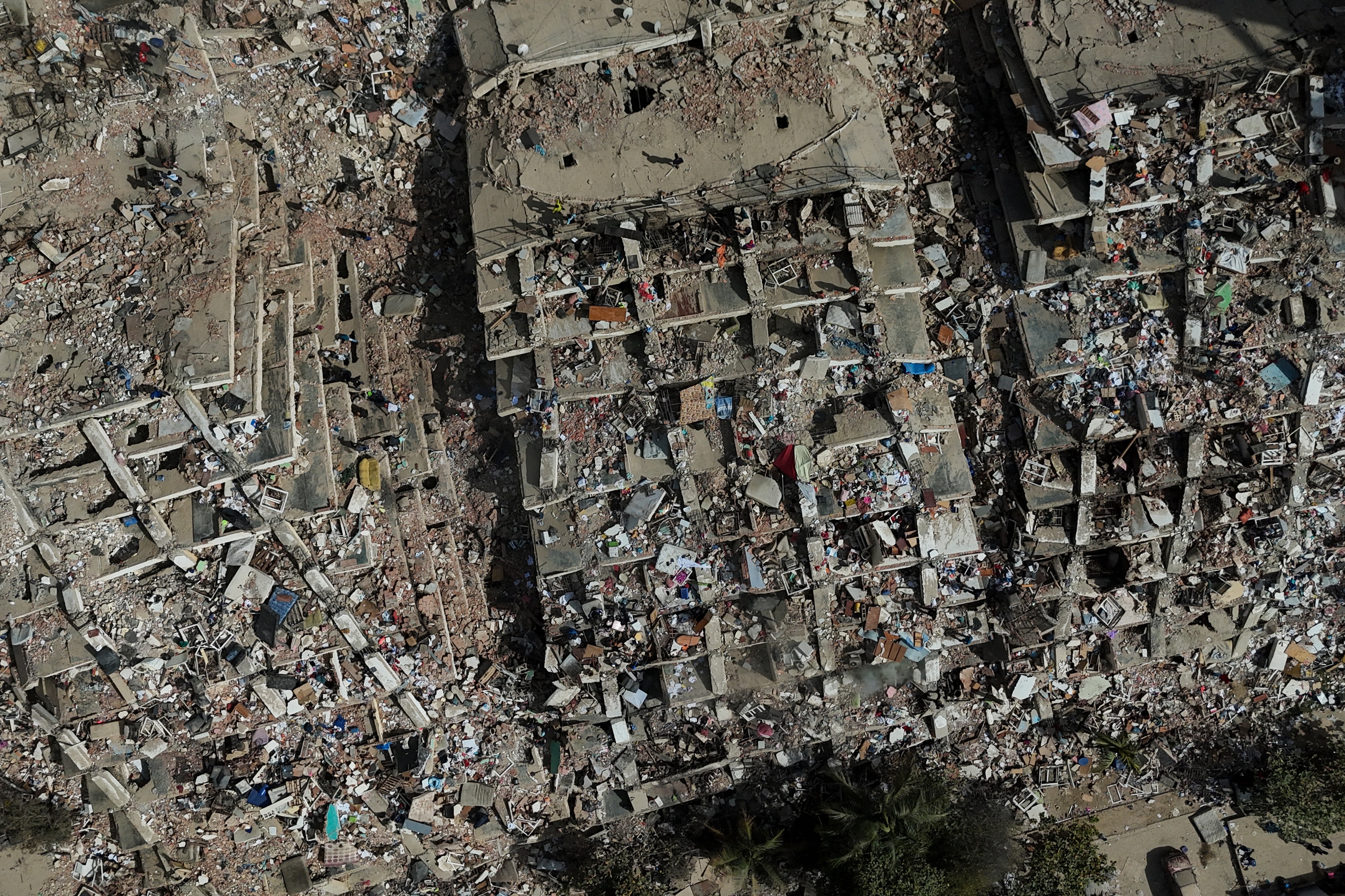 An aerial shot of a large area cluttered by concrete rubble where tower buildings have collapsed.
